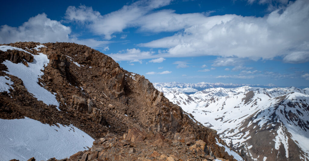 Rocky summit terrain on Mount Elbert with snow-covered Sawatch Range peaks beyond