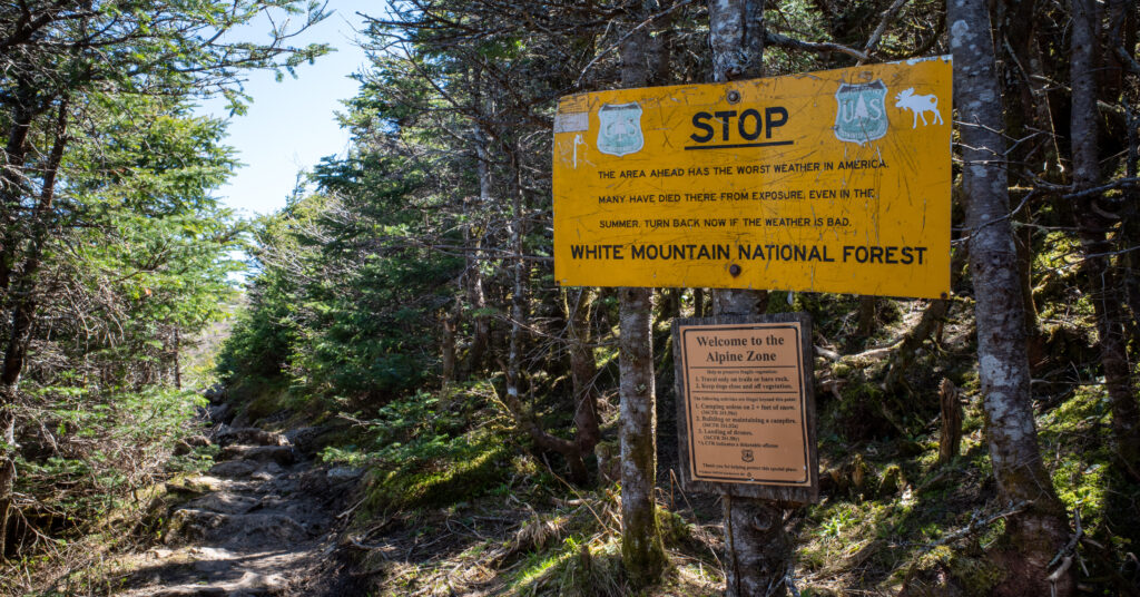 Weather and alpine-zone warning signs beside the rocky upper Edmands Path