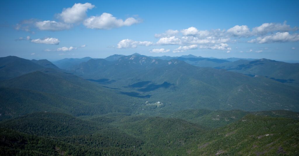 Adirondack High Peaks beneath scattered clouds from Giant Mountain's summit.