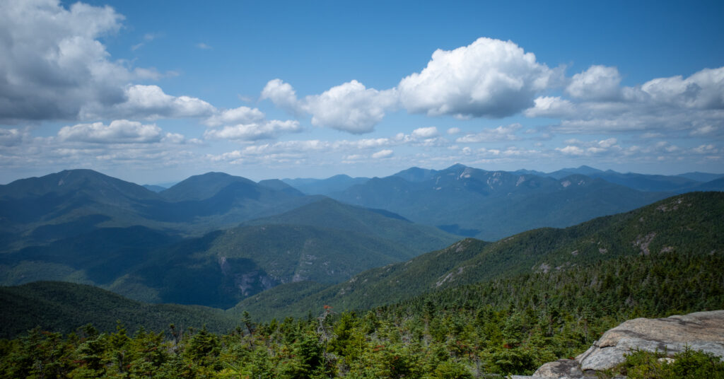 Broad High Peaks panorama beneath billowing clouds from Rocky Peak Ridge.