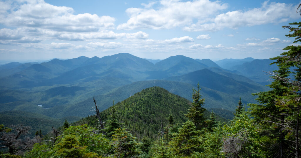 Layered Adirondack peaks framed by evergreens on Giant Mountain's descent.
