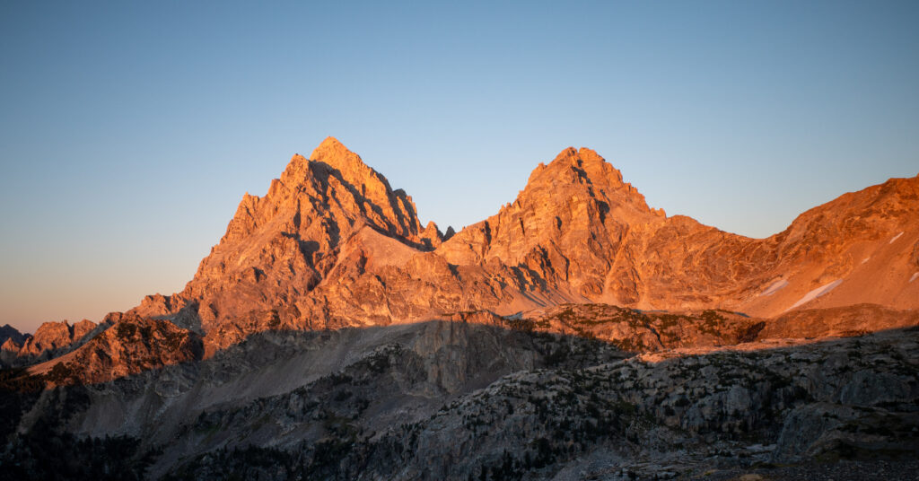 Grand Teton and Middle Teton lit orange at sunset from Hurricane Pass