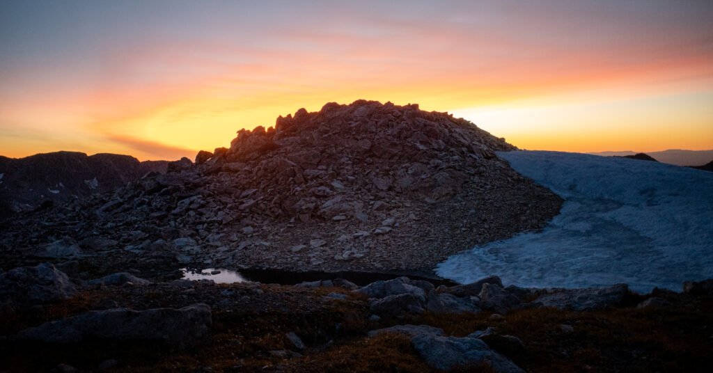 A rocky crest and lingering snow beneath the sunset sky at Paintbrush Divide